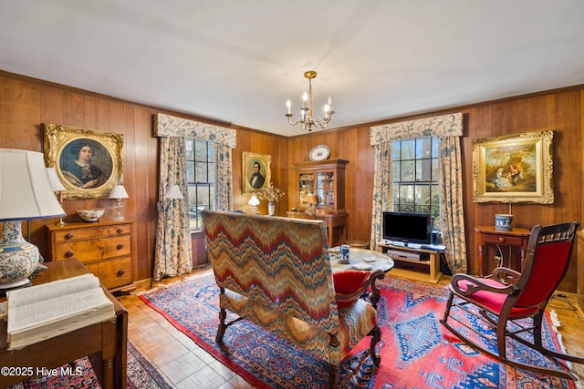 living room featuring crown molding, wooden walls, light parquet flooring, and a chandelier