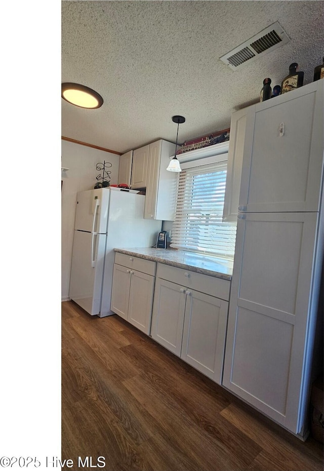 kitchen featuring decorative light fixtures, white cabinets, white fridge, dark wood-type flooring, and a textured ceiling