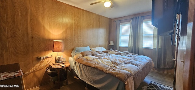 bedroom with hardwood / wood-style flooring, ceiling fan, and wood walls