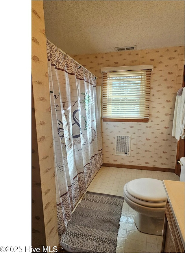 bathroom featuring a shower with curtain, vanity, toilet, and a textured ceiling