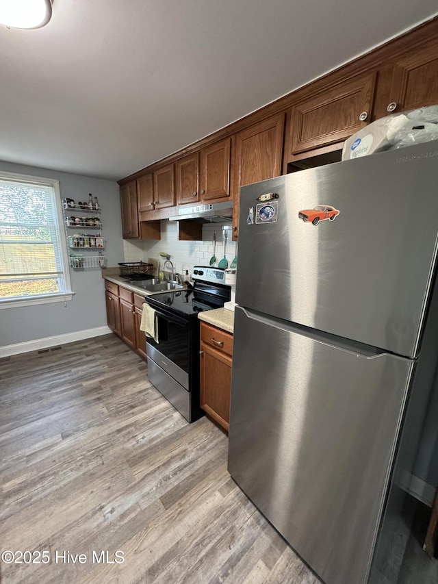 kitchen featuring stainless steel appliances, tasteful backsplash, sink, and light hardwood / wood-style flooring