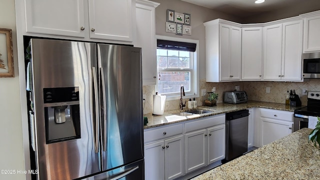 kitchen featuring sink, tasteful backsplash, light stone counters, appliances with stainless steel finishes, and white cabinets