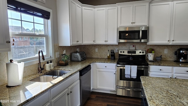 kitchen featuring sink, dark wood-type flooring, appliances with stainless steel finishes, light stone counters, and white cabinets