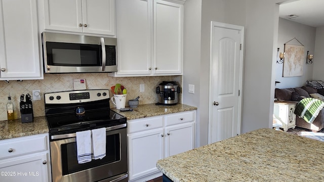 kitchen with light stone counters, stainless steel appliances, and white cabinets