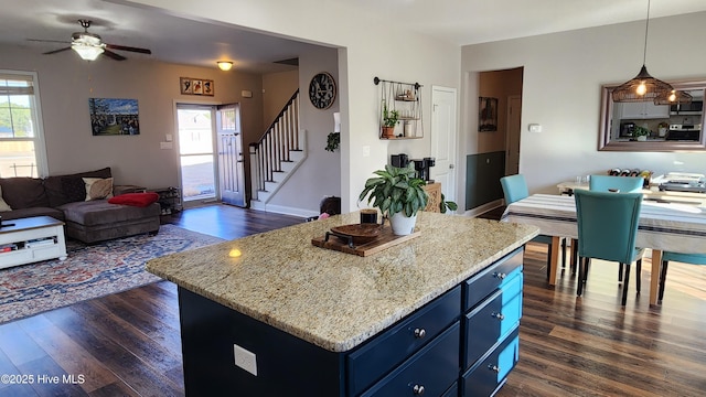 kitchen featuring blue cabinetry, dark hardwood / wood-style floors, a kitchen island, and pendant lighting