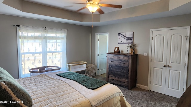 bedroom with a tray ceiling, ceiling fan, and carpet flooring