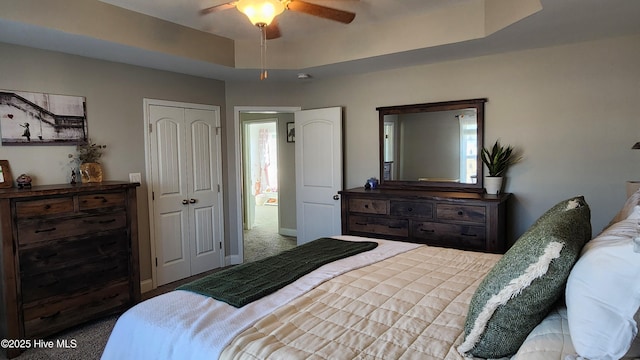 bedroom featuring a closet, a raised ceiling, ceiling fan, and carpet flooring