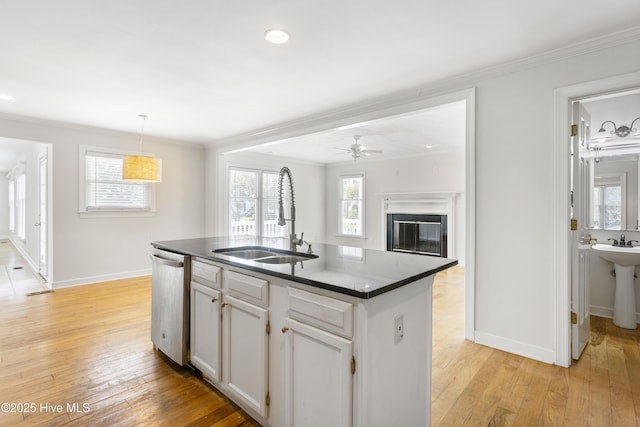 kitchen with sink, dishwasher, ornamental molding, white cabinets, and a center island with sink