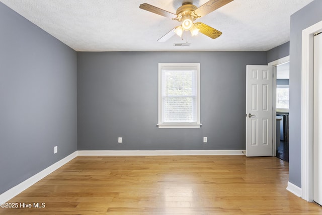 spare room with ceiling fan, light hardwood / wood-style flooring, and a textured ceiling