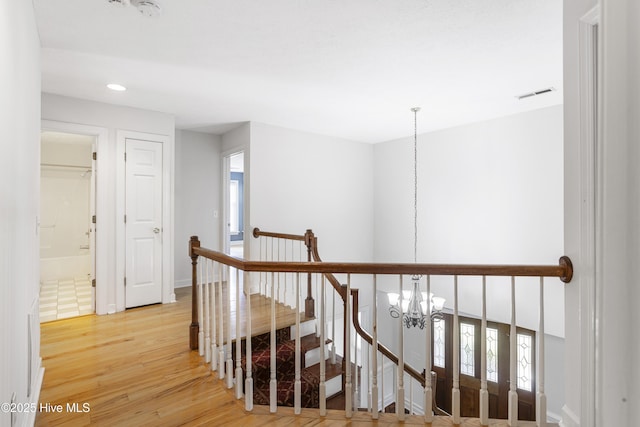 hall with hardwood / wood-style flooring and an inviting chandelier