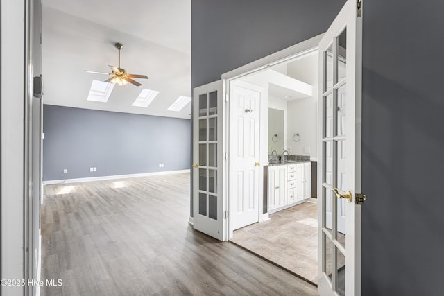 empty room featuring ceiling fan, light hardwood / wood-style floors, and vaulted ceiling