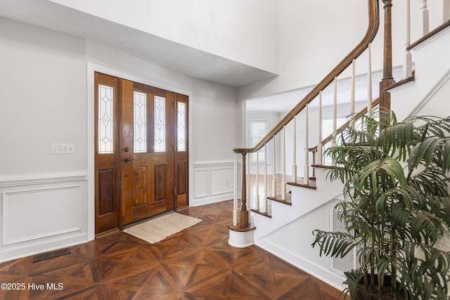 entryway featuring dark parquet flooring and a high ceiling