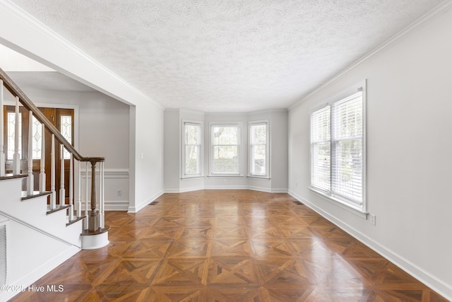 spare room featuring ornamental molding, dark parquet floors, and a textured ceiling