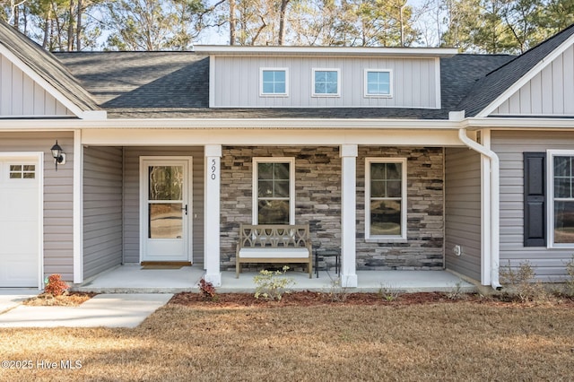 doorway to property with a porch, a garage, and a yard