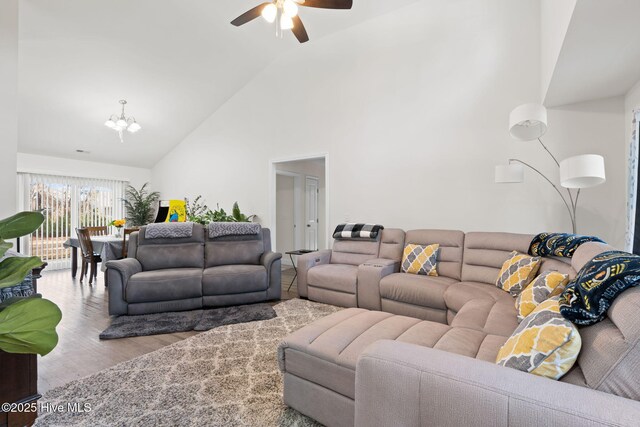 living room featuring hardwood / wood-style flooring, ceiling fan, and a towering ceiling