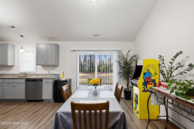 kitchen featuring hanging light fixtures, gray cabinets, stainless steel dishwasher, and hardwood / wood-style floors