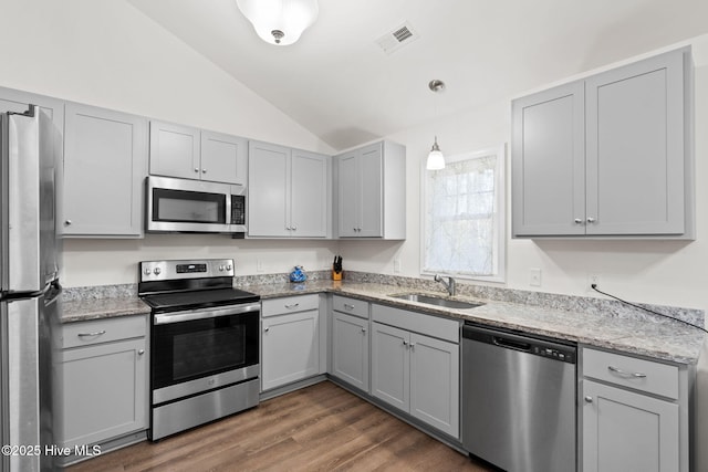 kitchen featuring gray cabinets, appliances with stainless steel finishes, decorative light fixtures, lofted ceiling, and sink