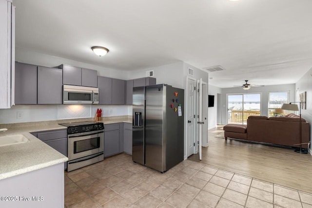 kitchen featuring stainless steel appliances, sink, gray cabinetry, and ceiling fan