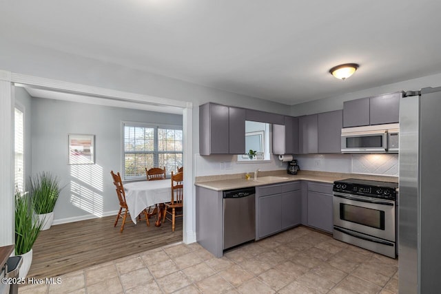 kitchen featuring tasteful backsplash, appliances with stainless steel finishes, gray cabinets, and sink