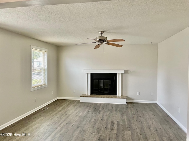 unfurnished living room featuring ceiling fan, hardwood / wood-style floors, and a textured ceiling