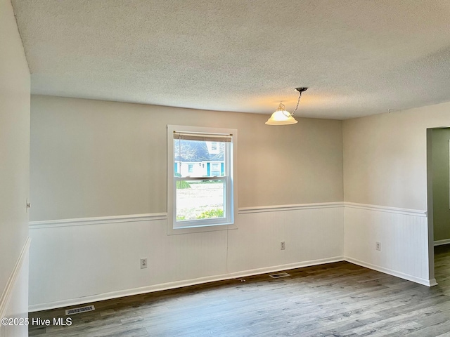 empty room with wood-type flooring and a textured ceiling