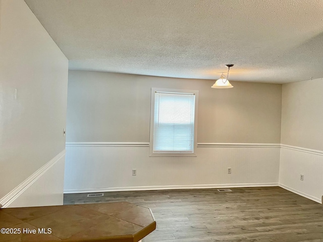 spare room with hardwood / wood-style floors and a textured ceiling