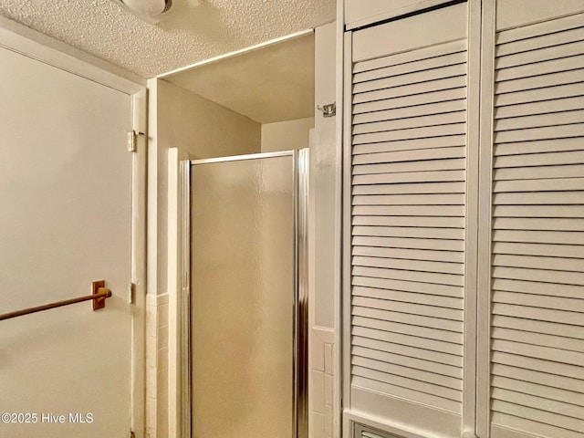 bathroom featuring a shower with door and a textured ceiling