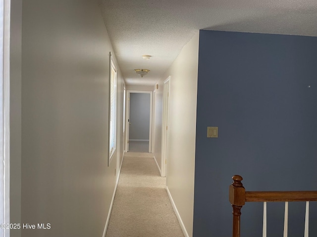 hallway featuring light carpet and a textured ceiling