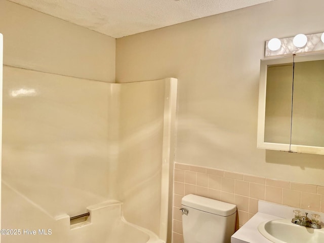 bathroom featuring tile walls, vanity, a shower, a textured ceiling, and toilet