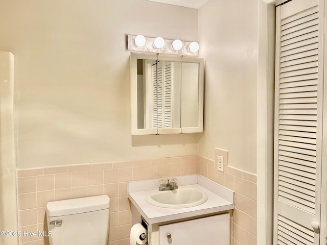 bathroom with vanity, tile walls, and toilet