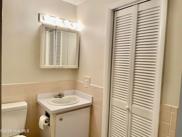 bathroom with vanity, toilet, and tile walls