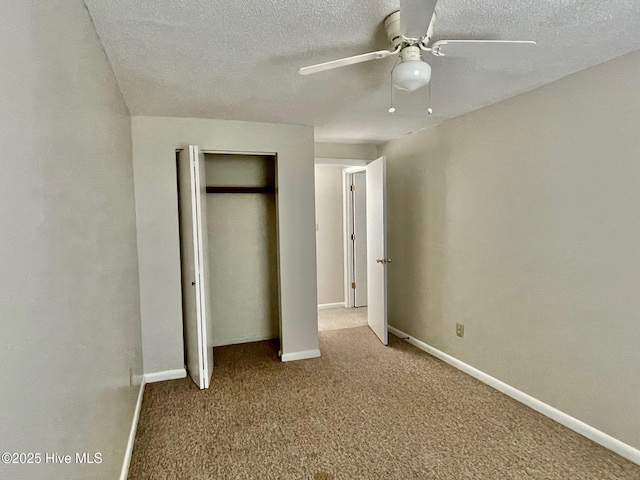 unfurnished bedroom with ceiling fan, carpet floors, a textured ceiling, and a closet