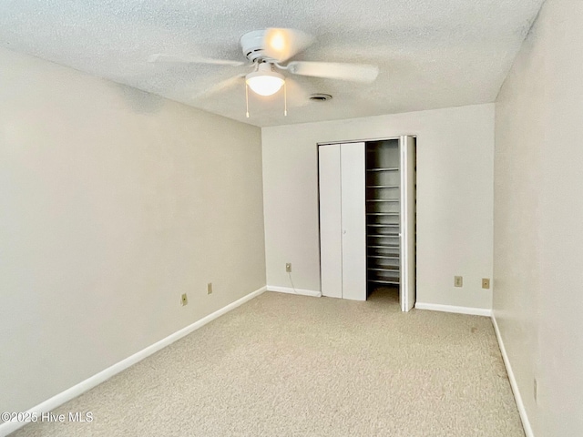 unfurnished bedroom with ceiling fan, light colored carpet, a textured ceiling, and a closet