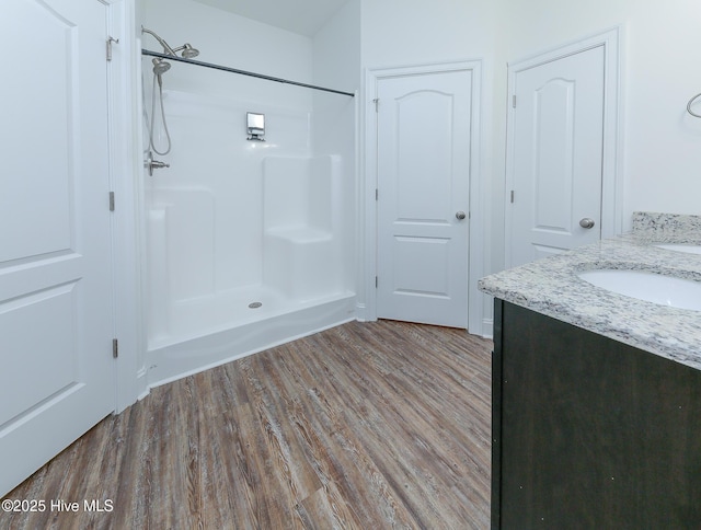 bathroom with hardwood / wood-style flooring, a shower, and vanity