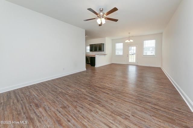 unfurnished living room featuring dark hardwood / wood-style floors and ceiling fan with notable chandelier