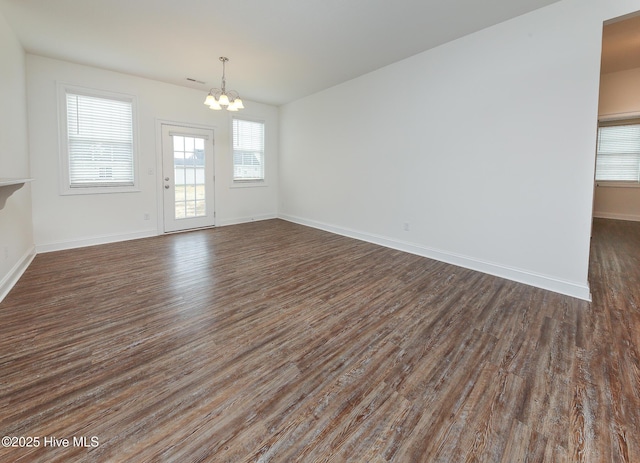 empty room featuring dark wood-type flooring and a notable chandelier