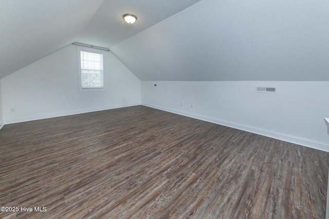 additional living space with vaulted ceiling and dark wood-type flooring