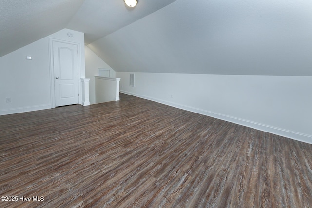 additional living space featuring lofted ceiling and dark hardwood / wood-style floors