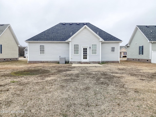 rear view of house with central AC and a lawn