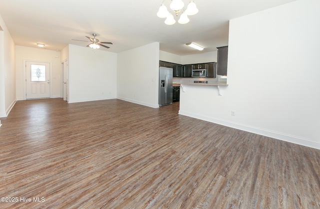 unfurnished living room with ceiling fan with notable chandelier and dark hardwood / wood-style flooring