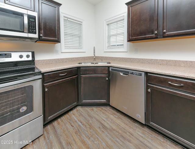 kitchen with stainless steel appliances, sink, dark brown cabinetry, and light wood-type flooring