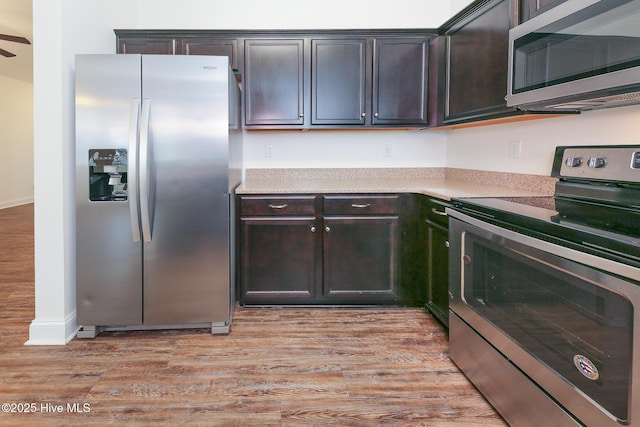 kitchen featuring stainless steel appliances, dark brown cabinets, and light hardwood / wood-style flooring