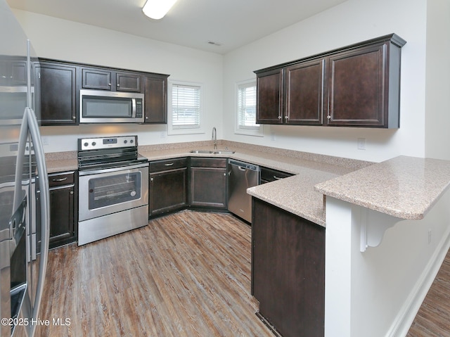 kitchen featuring dark brown cabinets, appliances with stainless steel finishes, kitchen peninsula, and a breakfast bar area