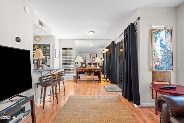 hall featuring light wood finished floors, baseboards, and visible vents