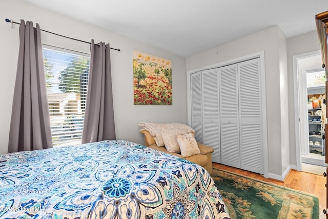 bedroom with a closet, baseboards, and wood finished floors