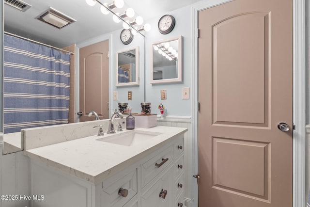 full bathroom featuring a wainscoted wall, visible vents, and vanity