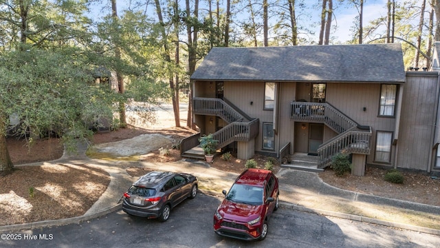 townhome / multi-family property featuring a shingled roof and stairway