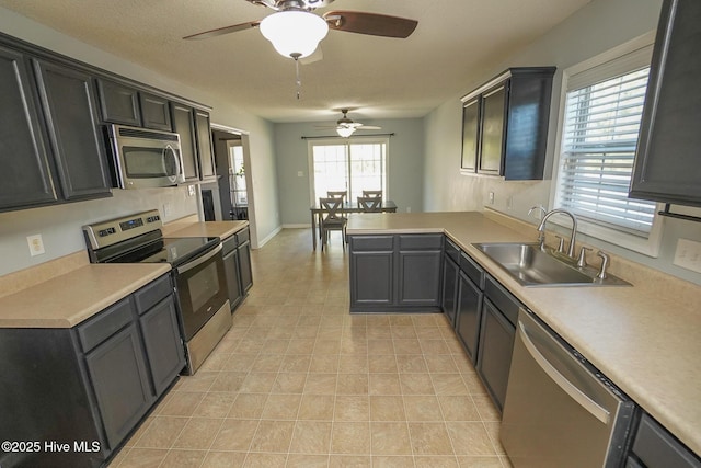 kitchen with sink, kitchen peninsula, a textured ceiling, and appliances with stainless steel finishes