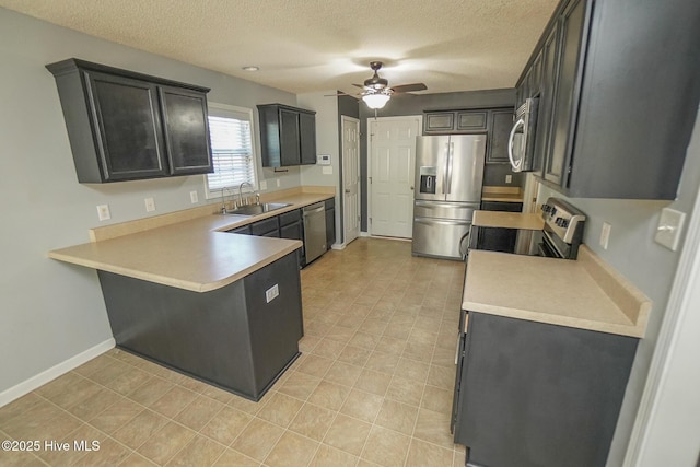 kitchen with appliances with stainless steel finishes, sink, ceiling fan, kitchen peninsula, and a textured ceiling