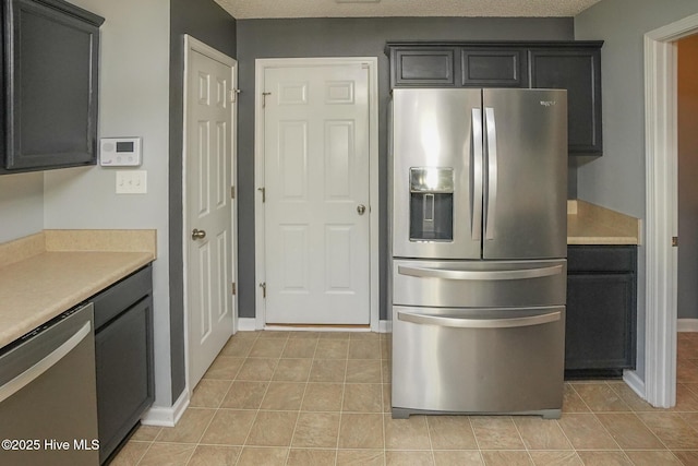 kitchen with appliances with stainless steel finishes, light tile patterned floors, and a textured ceiling